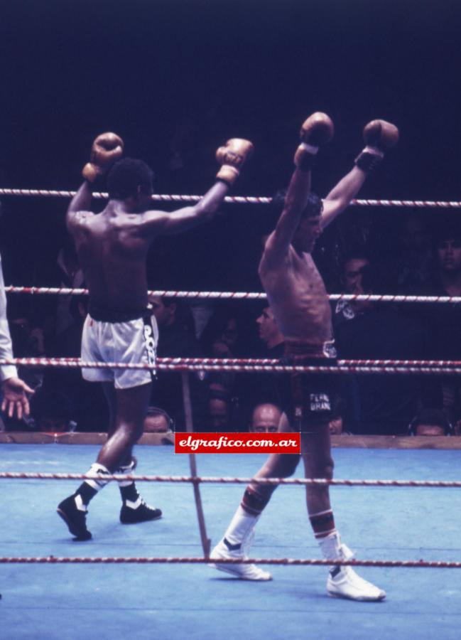 Imagen Ambos boxeadores con los brazos en alto. Uno celebra el triunfo, el otro el esfuerzo realizado ante uno de los mejores de la historia.