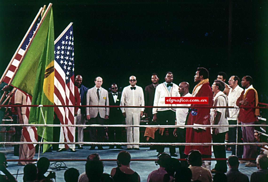 Imagen Ceremonia previa. Junto a las autoridades del C.M.B. encabezadas por el señor Velázquez, Foreman y su manager Dick Saddler comienzan a escuchar al incansable Cassius Clay.